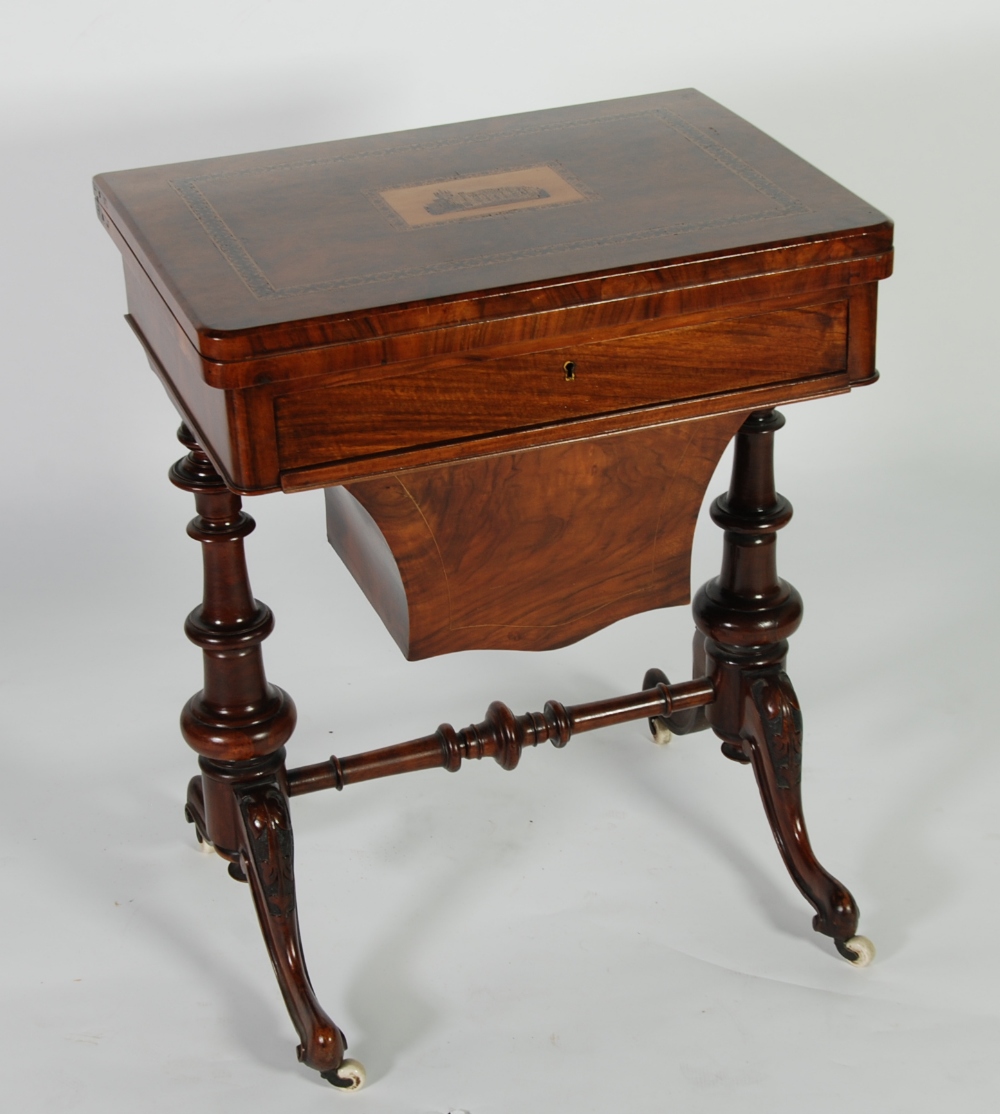 A MID VICTORIAN WALNUT SEWING/GAMES TABLE, the fold over swivelling top opening to reveal