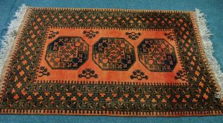 TURKOMAN RUG, with a row of three large Afghan black and brown stencilled guls on a brick red