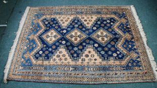 EASTERN RUG, with diamond shaped triple pole medallions on a dark blue ground with beige and sky