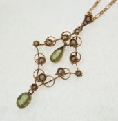 AN EDWARDIAN STAMPED 9CT GOLD, PERIDOT AND SEED PEARL OPEN WORK PENDANT, kite shaped with two pear
