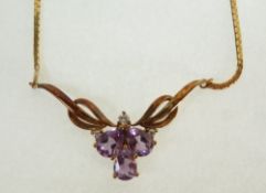 A 9CT GOLD AMETHYST AND DIAMOND PENDANT NECKALCE, the bow pattern front set with three pear cut