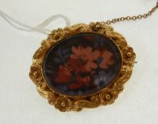 A GOLD SMALL OVAL GLAZED LOCKET BROOCH, with floral cast border and glazed front, inscription verso,