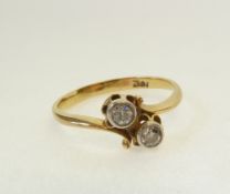 A STAMPED 18CT GOLD TWO STONE DIAMOND CROSS OVER RING, each bezel set brilliant cut diamond 0.10ct