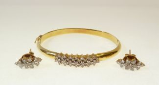 A GOLD AND DIAMOND HINGE OPENING BANGLE AND EARRING SET, the top of the bangle with 37 claw set