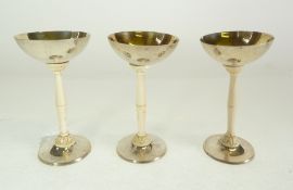 *SET OF THREE GERMAN SILVER COLOURED METAL AND PARCEL GILT SAUCER shaped liqueur goblets with tall