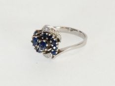 14K WHITE GOLD CROSS OVER RING set with ten small sapphires and six small diamonds, in tiered