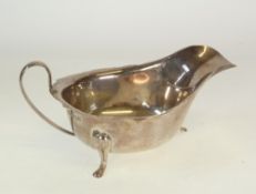 A SILVER SAUCE BOAT BY VINERS, with cyma edge, scroll handle and raised on three pad feet, Sheffield