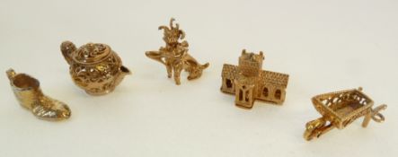 FOUR 9CT GOLD CHARMS; teapot, wheelbarrow, dog with a shoe and a church opening to reveal an