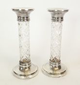 A PAIR OF SILVER MOUNTED CANDLE STICKS, WITH MOULDED GLASS STEMS, with weighted silver circular