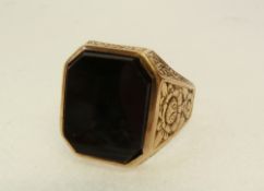 A GENT`S GOLD SIGNET RING, with broad foliate engraved shoulders and black stone inset top, 7.9g