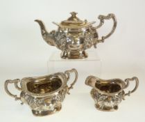 AN EDWARDIAN SILVER THREE PIECE BACHELOR TEA SET, bombe shape with repousse foliate decoration and