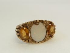 A 9CT GOLD RING SET WITH AND OVAL OPAL (chipped) AND FLANKET BY TWO ORANGE STONES, with scroll