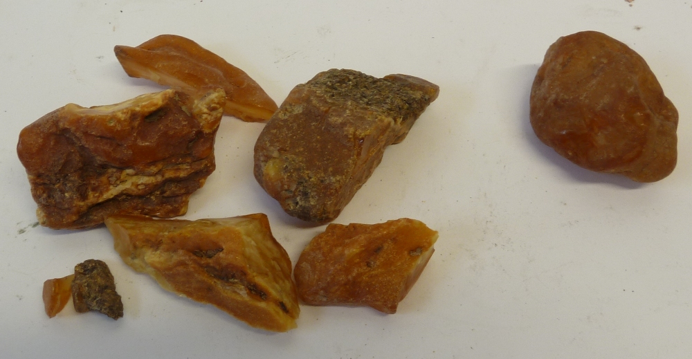 FIVE PIECES OF ROUGH AMBER, 110g, and a possibly rough carnelian specimen