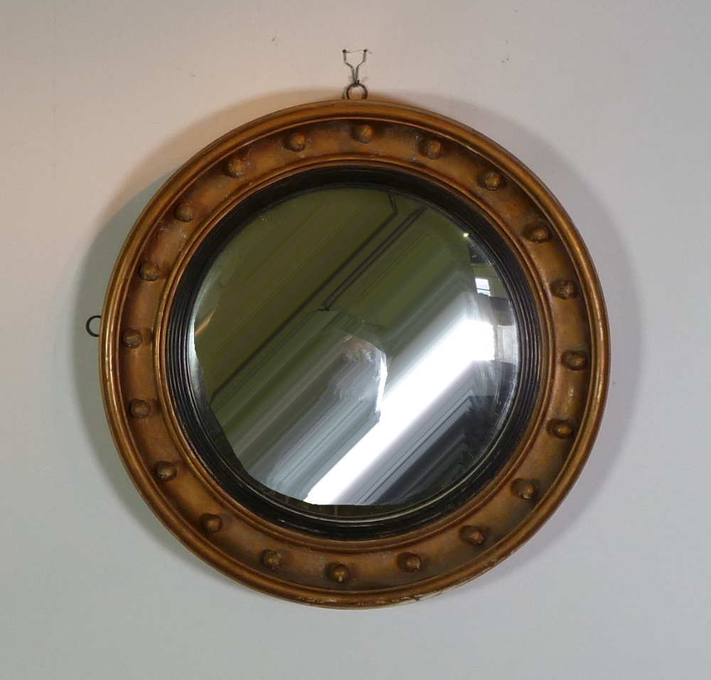 REGENCY STYLE GILTWOOD CONVEX WALL MIRROR, the circular plate within an ebonised reeded slip and