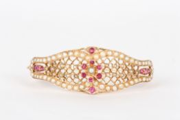 A Victorian style ruby and seed pearl stiff bangle, set with rubies and seed pearls in trellis