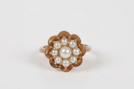 A 9ct gold seed pearl flower head ring, with central pearl surrounded by eight smaller pearls, size