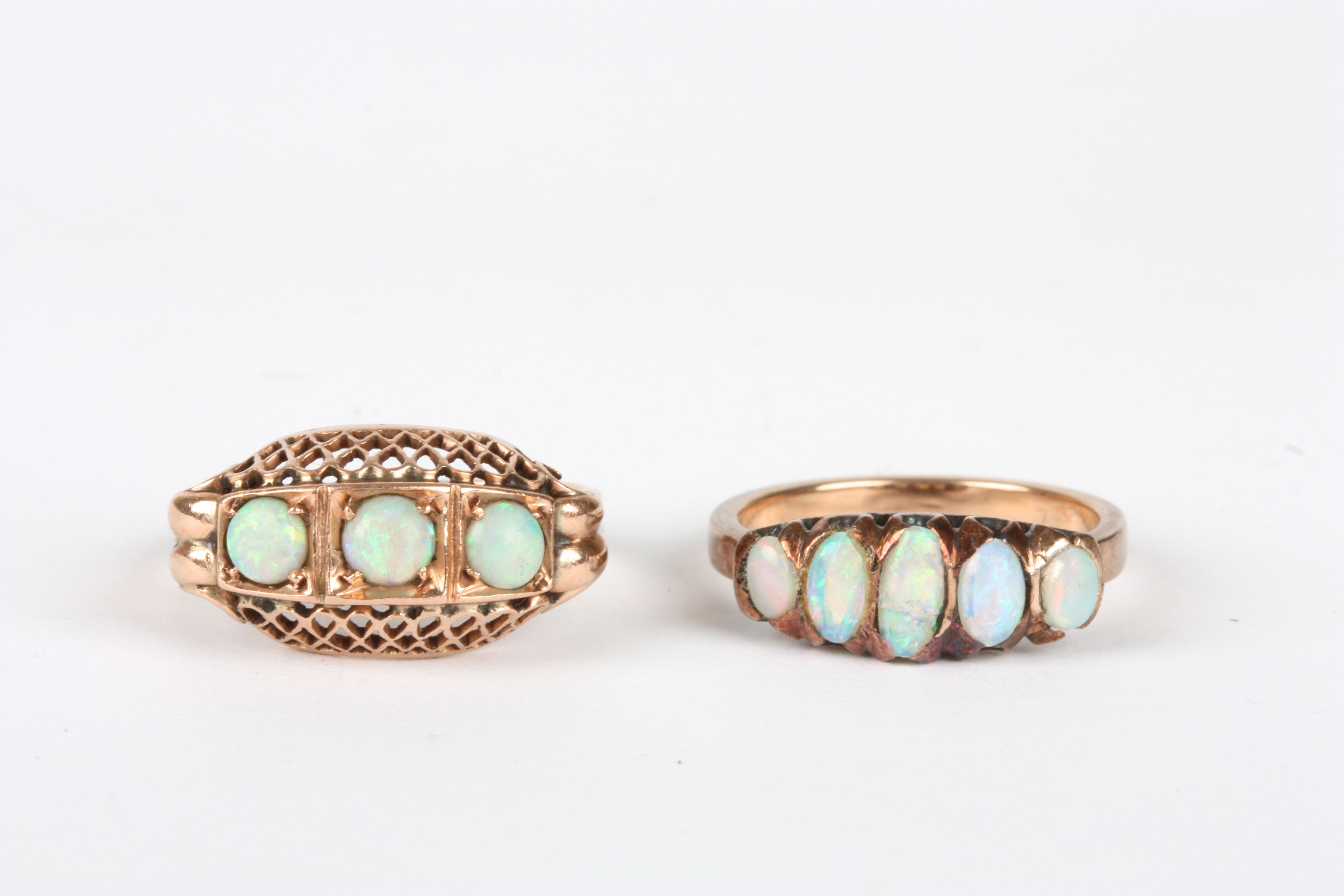 Two gold coloured metal opal rings, one set with three opals in pierced trellis shaped setting and