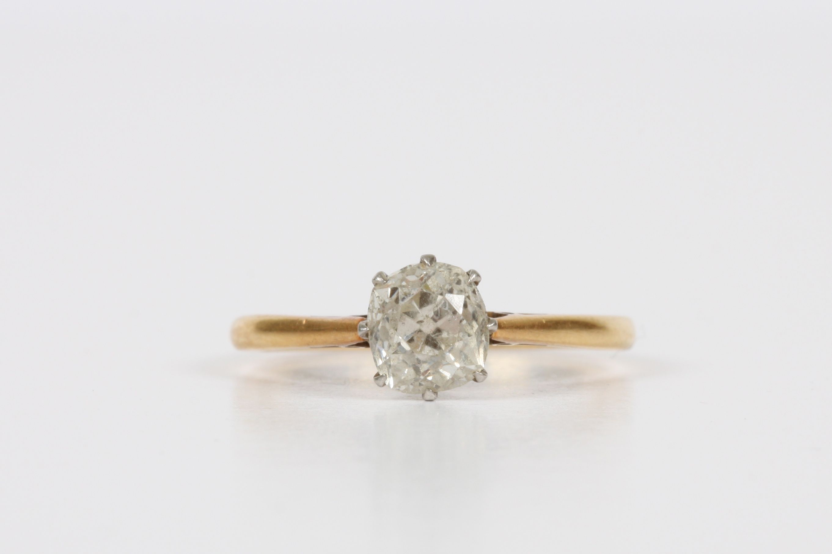 An 18ct gold and platinum solitaire ring, cushion cut, approximately one carat, in claw setting,