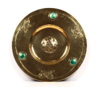 A large Arts & Crafts brass and enamel charger, decorated with a central embossed entwined roundel,