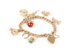 A charm bracelet, the curb link bracelet with eight charms attached and padlock clasp, unmarked but