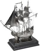 A silver model of a sailing ship, the ship with three masts in full sail, the deck with applied