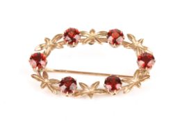 An oval shaped 9ct gold garnet brooch, set with six garnets, diameter 4cm  In good overall