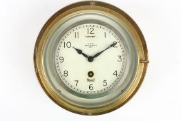 A brass eight day bulkhead clock, with Arabic numerals, and retails stamp for Mercer, England, 24.