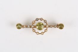 An Edwardian gold, seed pearl and peridot bar brooch, set with three peridots, the central one