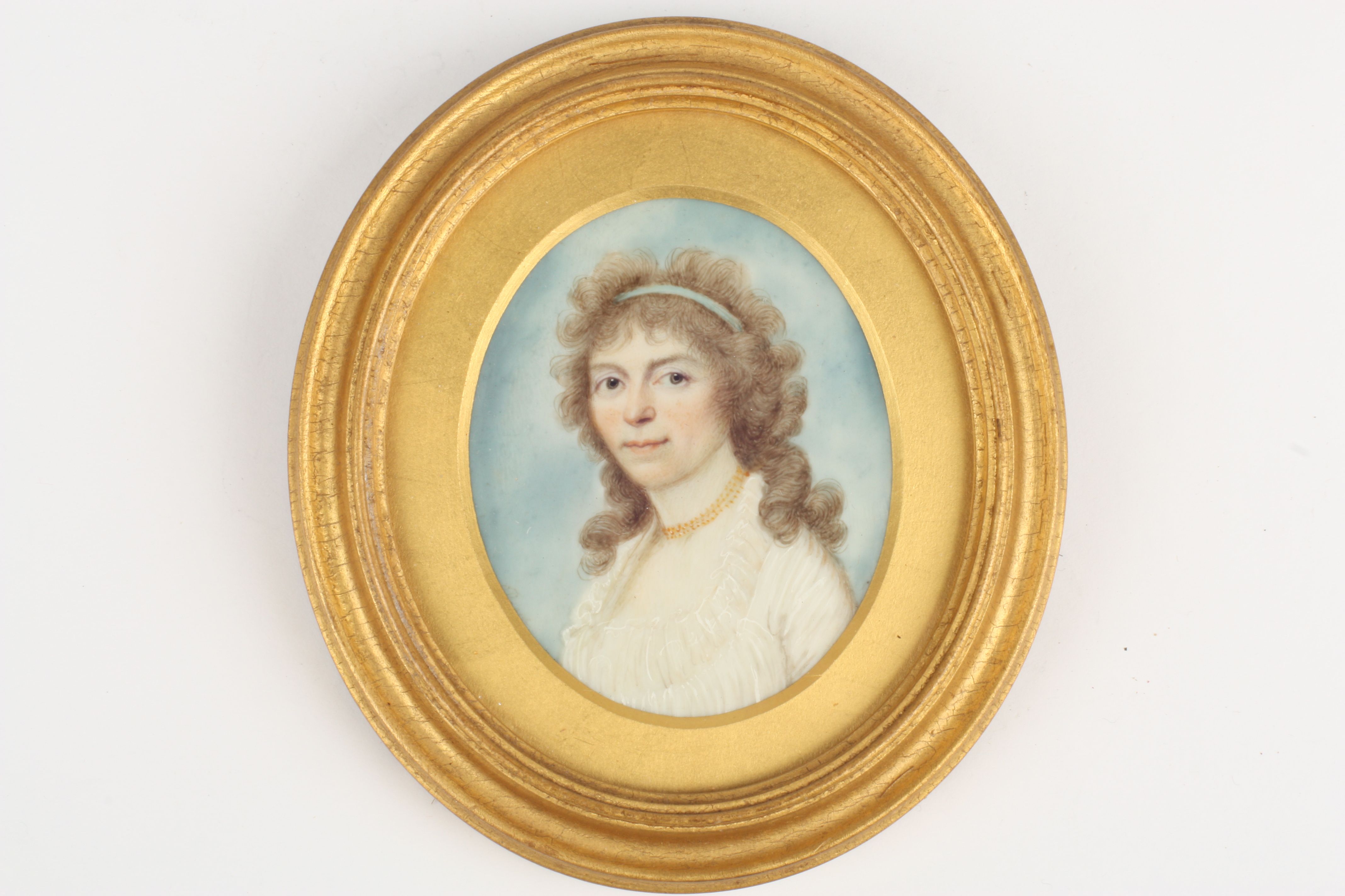 An early 19th century miniature portrait of a lady, painted on ivory, the sitter with flowing