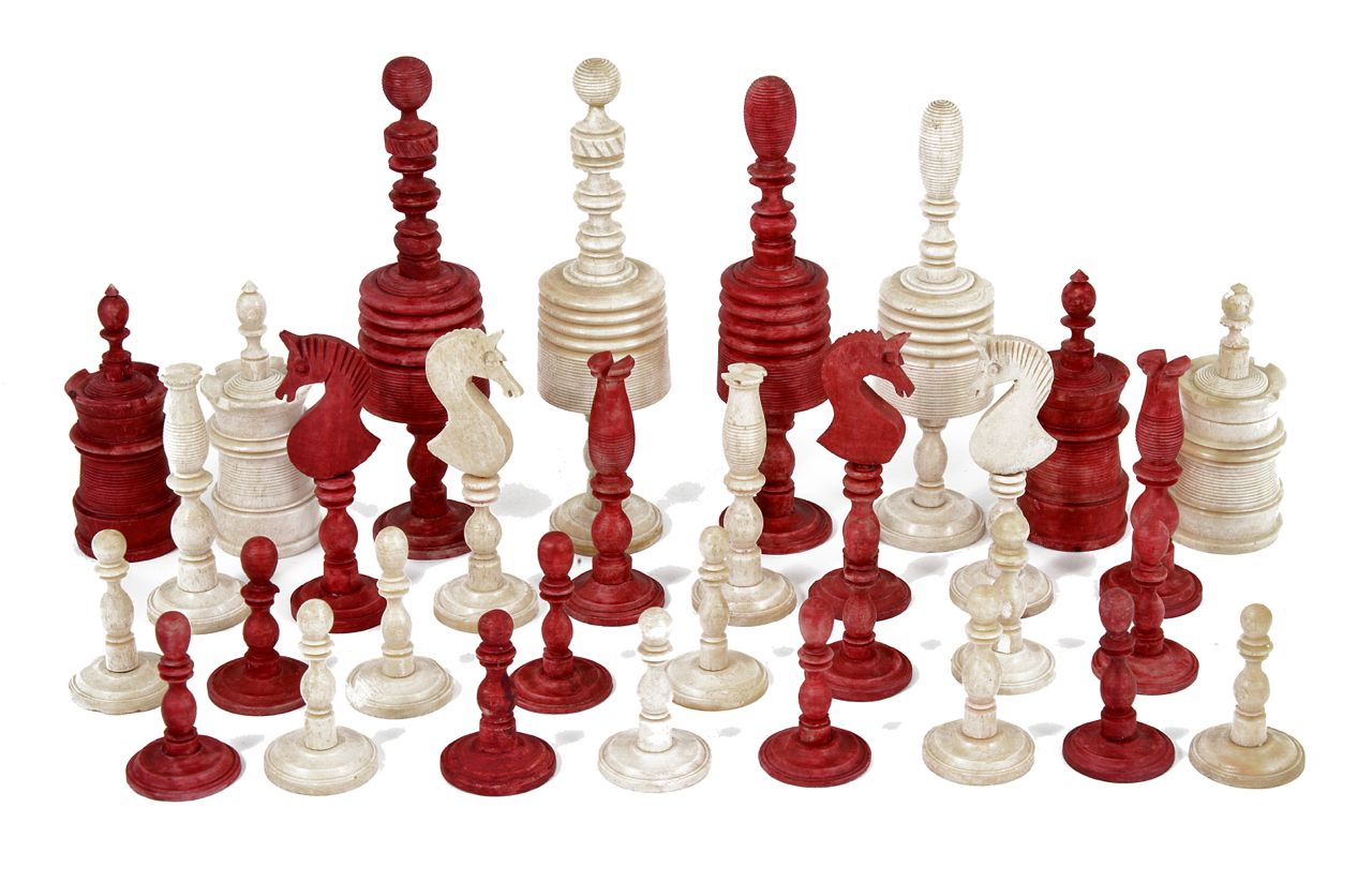 An early 20th century carved and stained bone chess set, with unstained and red stained pieces, of