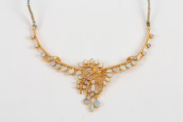 A gold coloured metal and opal stiff necklace, set with numerous opals in swirl shaped setting, on