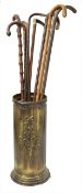 An early 20th century embossed brass stick stand and walking sticks, with eight assorted wooden