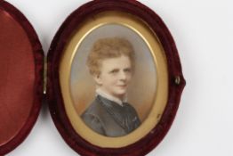 A late 19th century miniature portrait of a lady, painted on ivory, the sitter wearing a dark blue