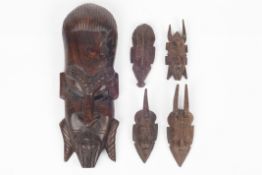 A large African carved rosewood tribal mask, together with four miniature carved tribal masks,