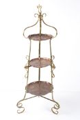 An Arts and Crafts three tiered cake stand, the brass stand with three graduated copper trays with