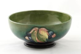 A Moorcroft `Fruit and leaf` small bowl, 1930s, with tube lined decoration on green ground, with