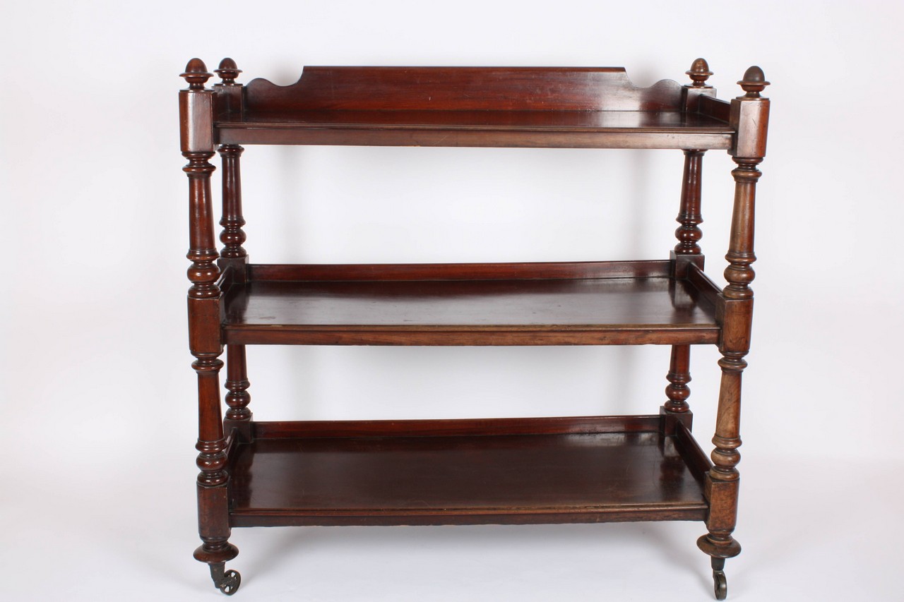 A Victorian mahogany three tier buffet, supported on turned and tapering columns to saucer feet