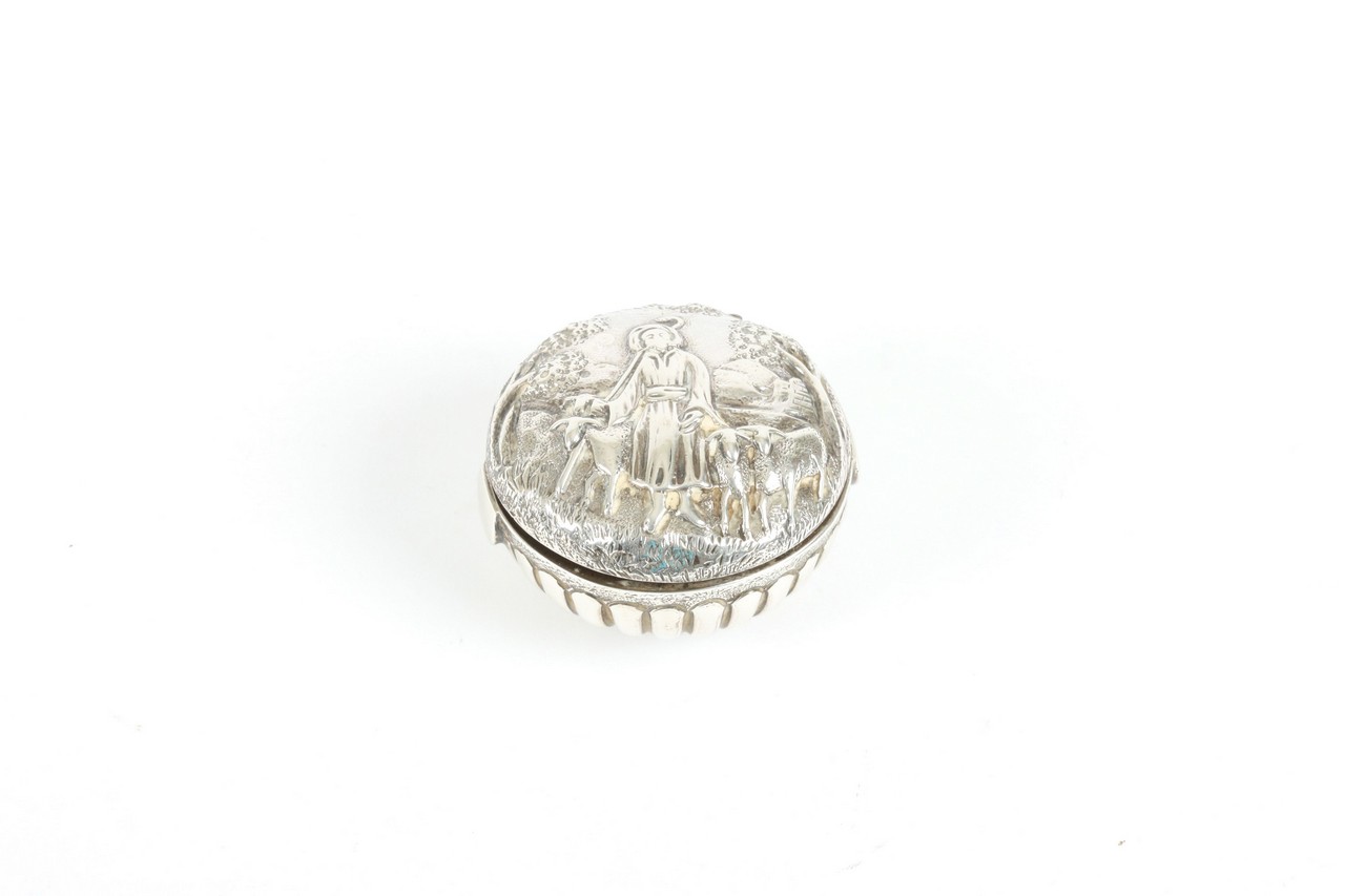 A small silver pillbox, hallmarked Birmingham 1869, the lid with repoussé decoration of goat herd