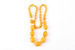 A string of graduated amber beads, 33cm long, the largest bead 3cm