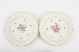 A Pair of 19th century French porcelain plates, painted with vignettes of flowers, with moulded