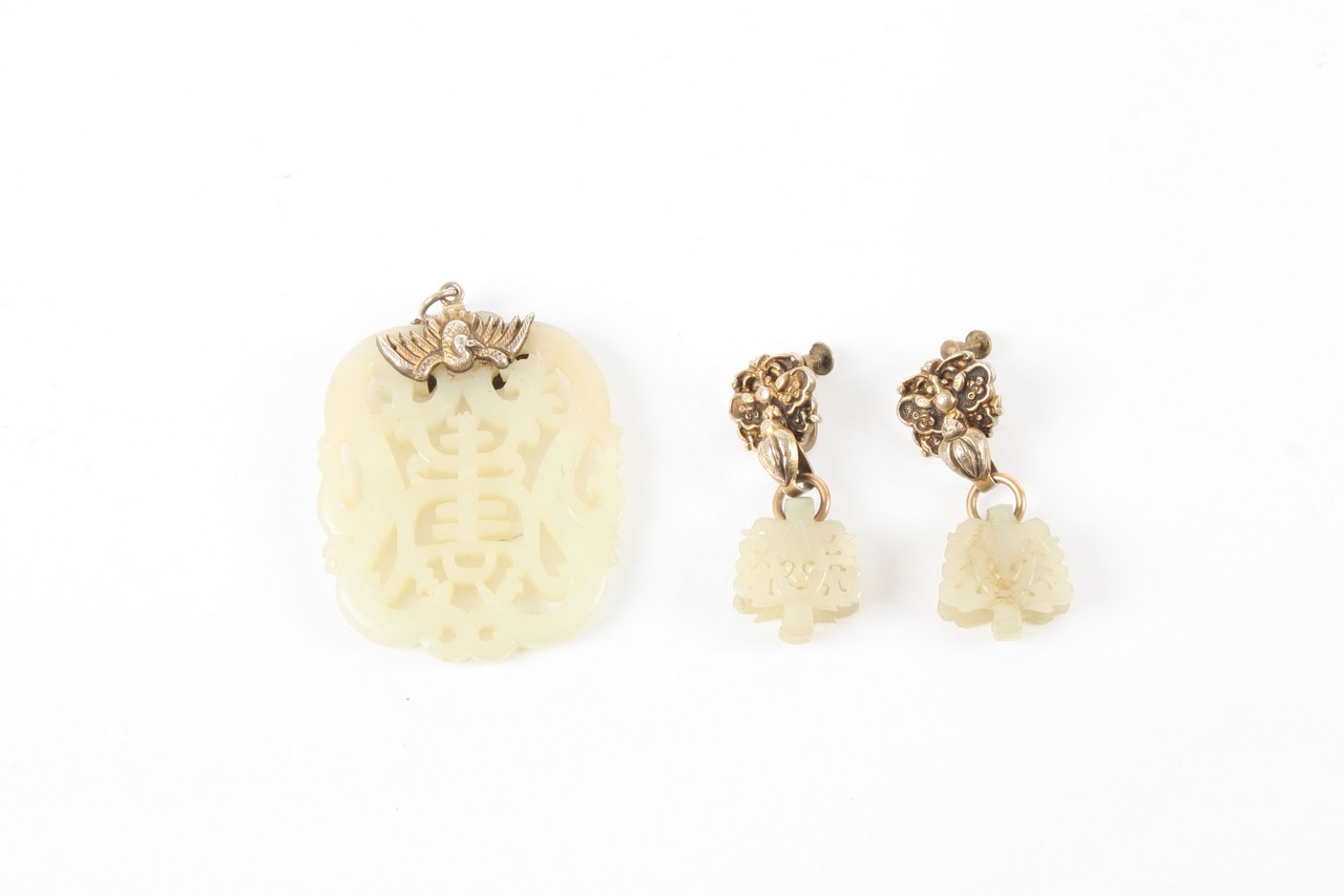 A Chinese mutton fat jade carved and pierced pendant and matching earrings, with silver coloured