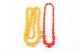 A set of yellow graduated amber beads, together with another plastic set of beads, the longest