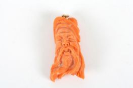 A Chinese carved coral head of an immortal, with ringed top. 4.5cm long Slight pitting to reverse.