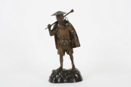 A Japanese bronze figure, probably circa 1900, the standing figure wearing a traditional hat and