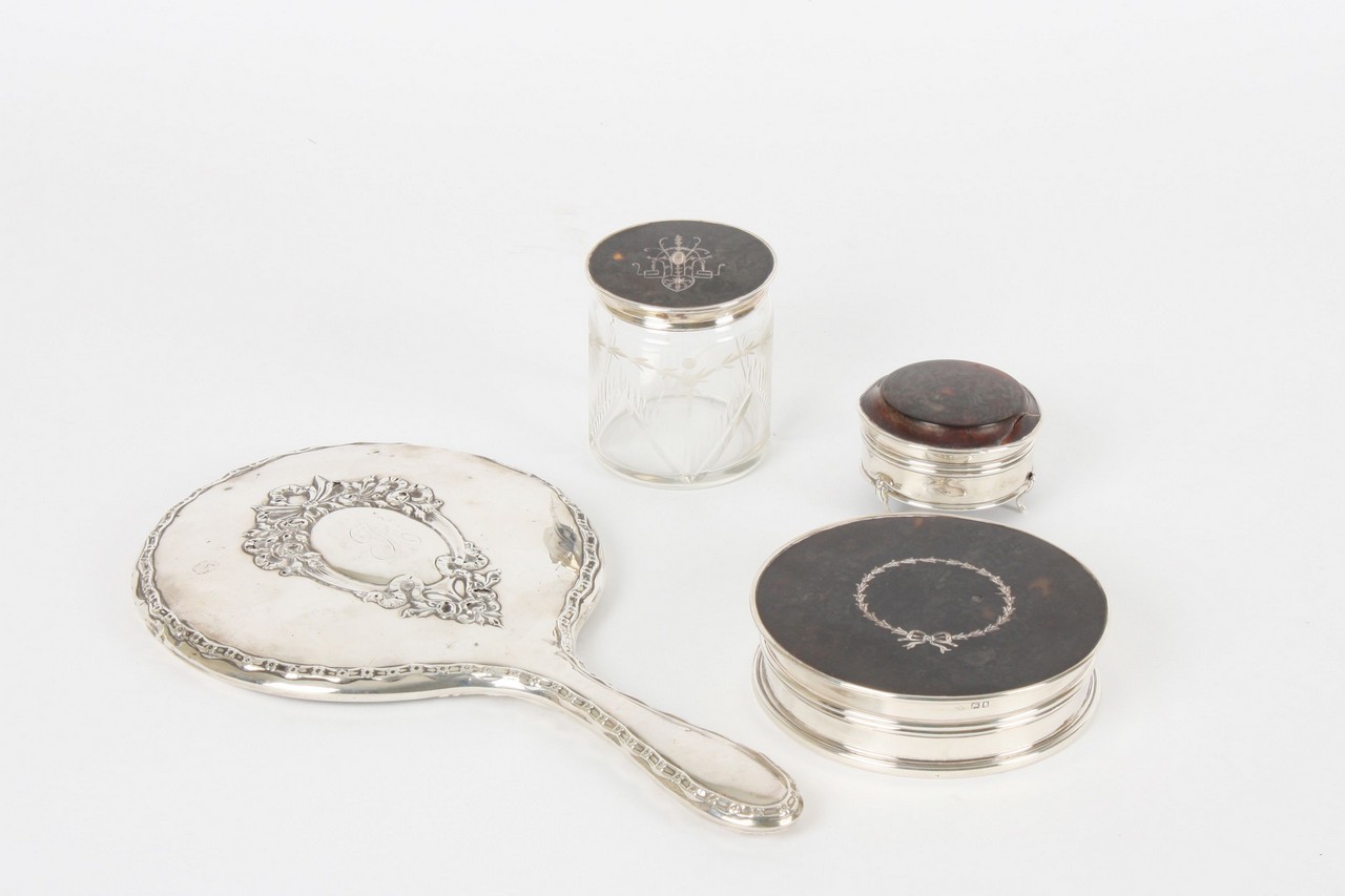 Four late 19th century dressing table items, comprising a silver backed hand mirror decorated with