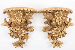 A pair of 20th century carved gilt wood wall brackets, heavily carved with flowers, birds and