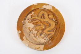 A 19th century Chinese pottery tile, the circular tile with mustard glazed decoration of dragon in