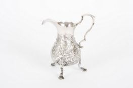 An 18th century silver cream jug, with repoussé decoration of scrolls and foliage, replaced