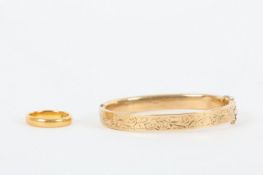 A 22ct gold wedding band and 9ct gold bangle, the stiff bangle engraved on one side Both appear to
