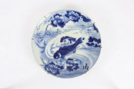 A large Japanese blue and white charger, hand painted with two koi fish surround by waters, trees
